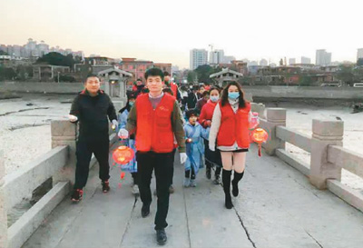 图为孩子们和志愿者一起走过古桥，祈福新年。（主办方供图）