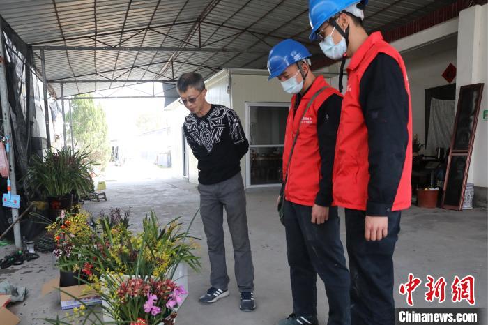 供电公司工作人员听台商介绍刚装盆的兰花。　刘伟玲 摄