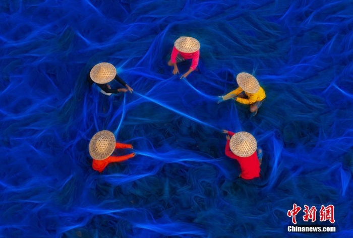 印度渔民修补蓝色渔网 似置身深邃海洋