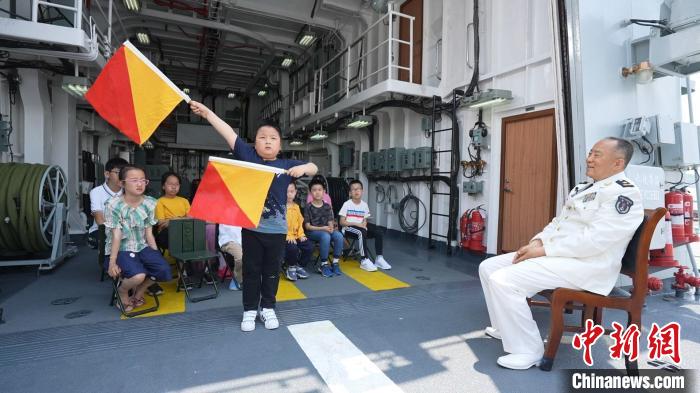 张华臣将军在舰船上教孩子们学习旗语。　王晓旭 摄