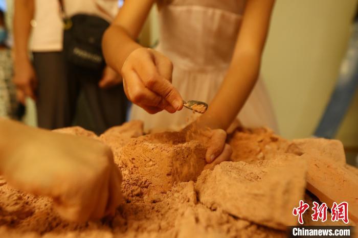 图为一位女孩正在对打开的“考古盲盒”进行“考古发掘”。　刘占昆 摄