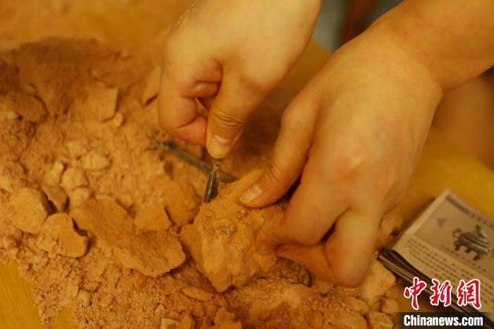 图为一位女孩小心翼翼地使用“考古铲”对“考古盲盒”进行“考古发掘”。　刘占昆 摄