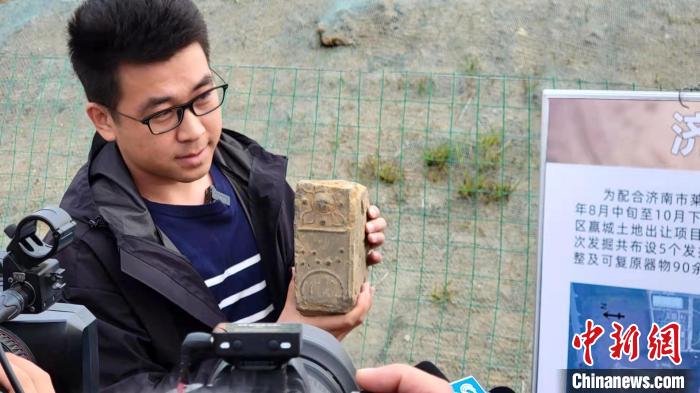 考古人员向媒体记者介绍汉砖的特点。　济南市考古研究院供图