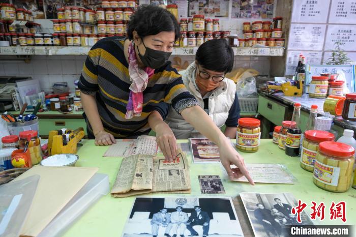 廖晃业和母亲翻开具历史价值的旧报刊和照片。　陈永诺 摄