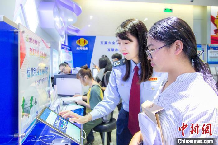 资料图：税务人员帮助纳税人通过电子税务办理业务。　杨锐轩 摄
