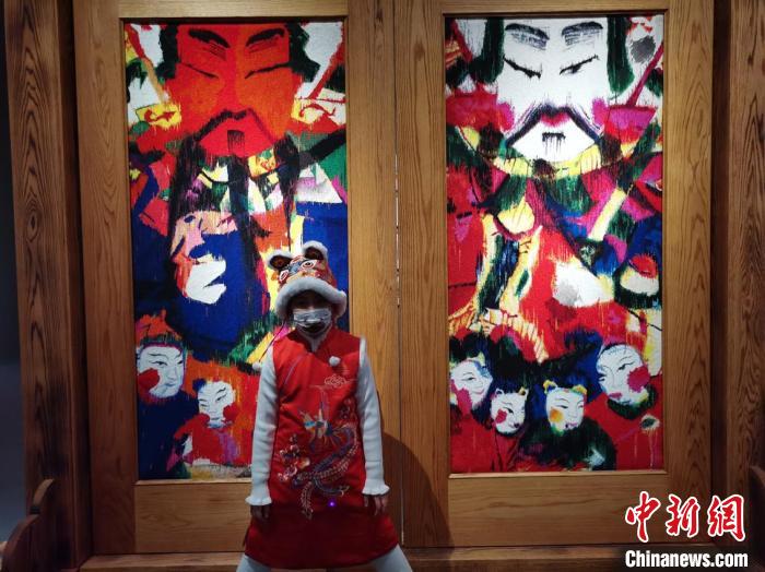 今年1月29日，一名小女孩在国博“到民间去”民艺展上与门神装置合影。