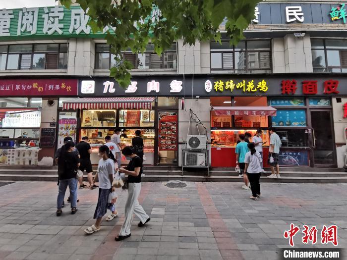 资料图：市民在街边小店购买小吃。 韩章云 摄