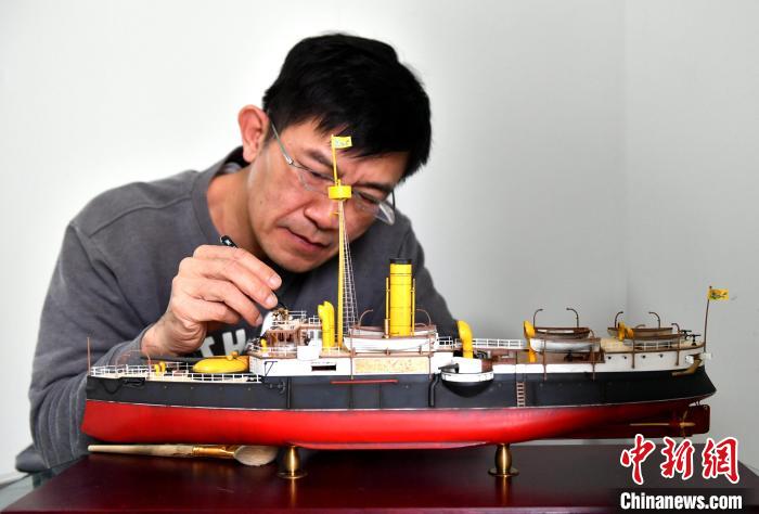 图为：高英智正在调整1：100的“平远”船仿真模型。　吕明 摄
