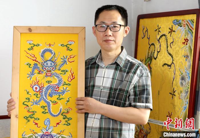 郭庆生与他的作品《海水江崖平针打籽云龙纹图》。　吕明会 摄