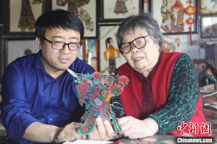 张雅君(右)在传授徒弟皮影雕刻技艺 。　朱大勇 　摄