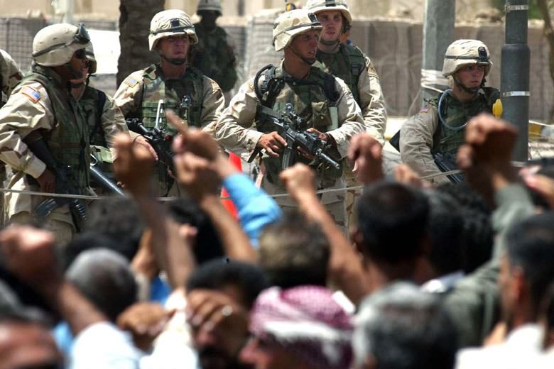 这是2003年6月18日，美军士兵在伊拉克首都巴格达美英联军临时总部门前持枪面对数百名示威的前伊拉克军人。新华社记者赵建伟　摄