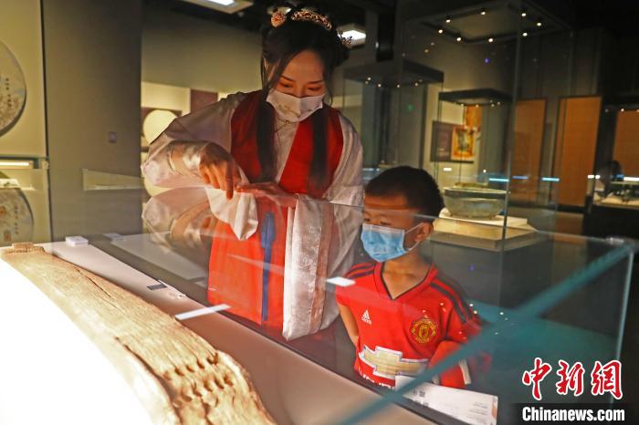 图为江西省博物馆讲解员徐晨颖(左)身穿汉服为小朋友讲解博物馆展出的文物“十三弦筝”。　刘占昆 摄