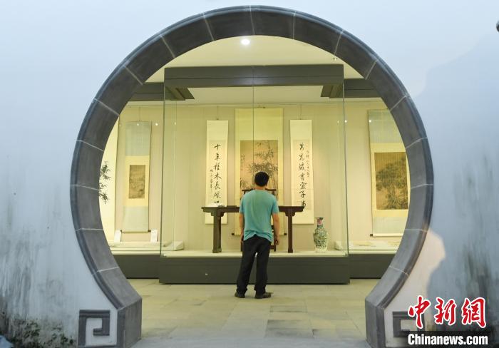 图为：游人在中国江南水乡文化博物馆的圆形门洞内参观书画作品。　王刚 摄