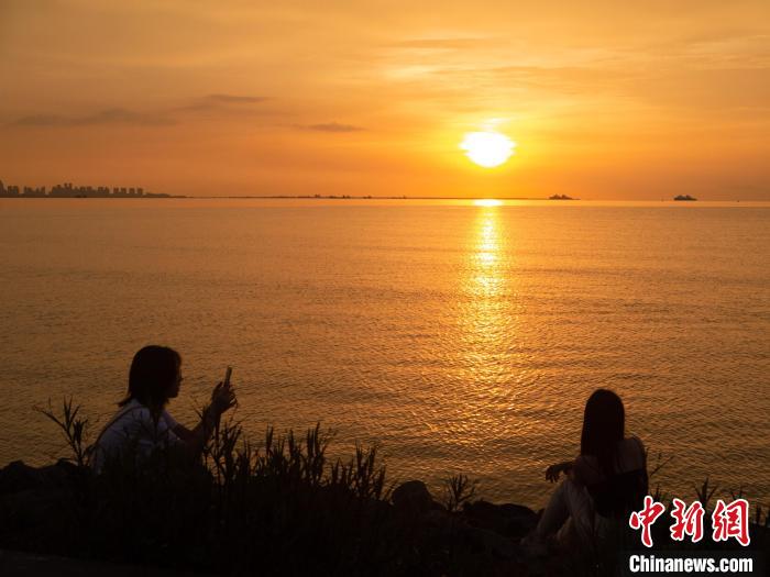 游客在海边与夕阳美景合影。　凌楠 摄
