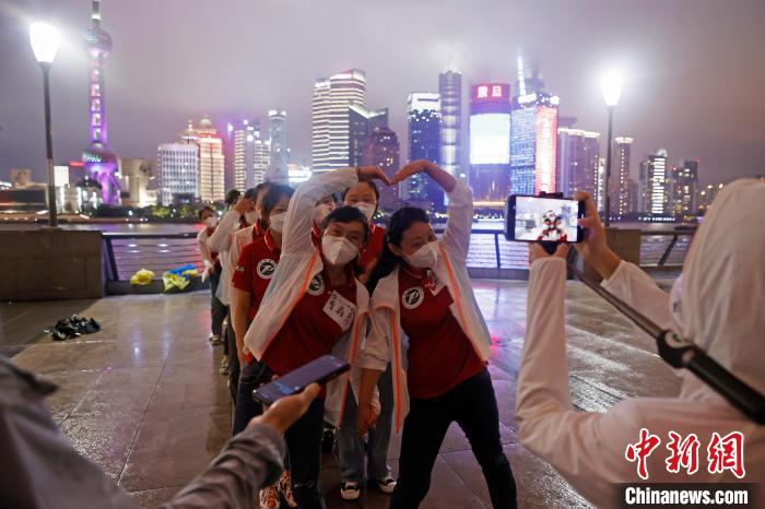 华中科技大学同济医学院附属同济医院援沪医疗队队员冒雨在外滩滨江步道上摆造型合影。　殷立勤 摄