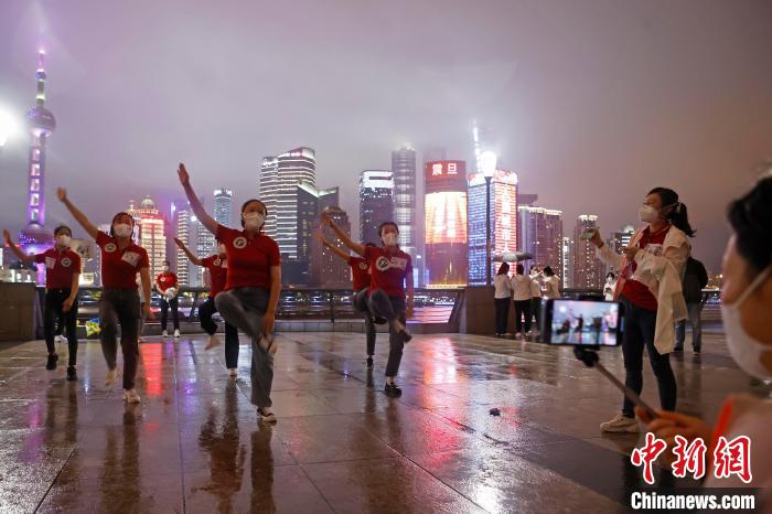 华中科技大学同济医学院附属同济医院援沪医疗队队员冒雨在外滩滨江步道上摆造型合影。　殷立勤 摄