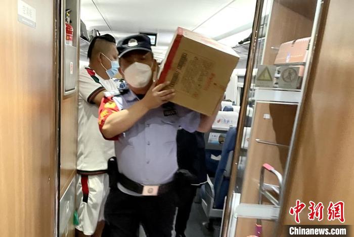 乘警扛着饼干等食物到车厢分发给旅客。　徐州铁路公安处供图