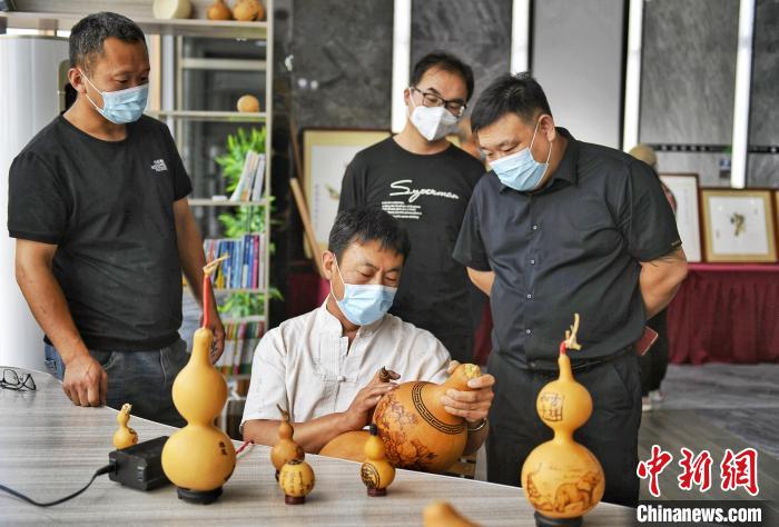 6月9日，丰润区非物质文化遗产传承人正在探讨葫芦烙画技艺。　赵亮 摄