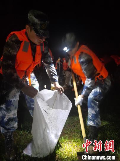 夜幕下，官兵戴頭燈裝填沙袋。　朱鵬 攝