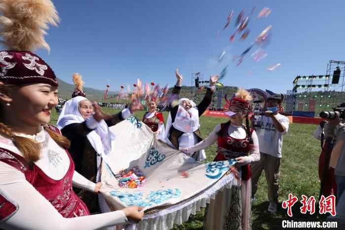 在草原上，遇到喜事，哈萨克族群众撒方糖、奶疙瘩等分享快乐。图为开幕式上的“恰秀”。　阿尔达克 摄