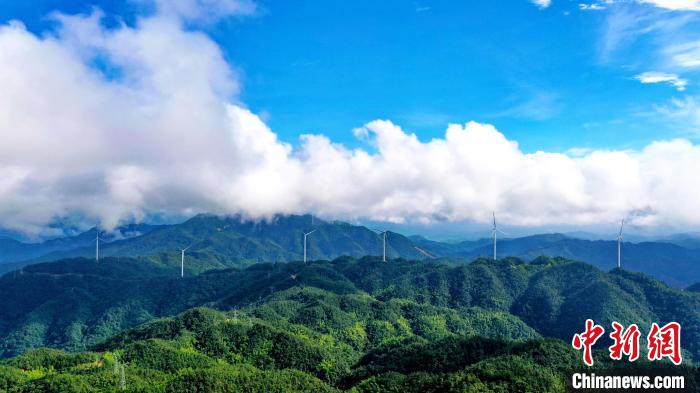 蓝天白云之下，高耸的风力发电机组与连绵的青山共同构成了一幅夏日美景图。　朱海鹏 摄