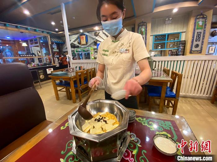 5月28日，呼和浩特市一家奶茶店里，服务员萨拙拉将黄油、炒米等奶茶“伴侣”放入热锅中。 <a target='_blank' href='/'>中新社</a>记者 张玮 摄