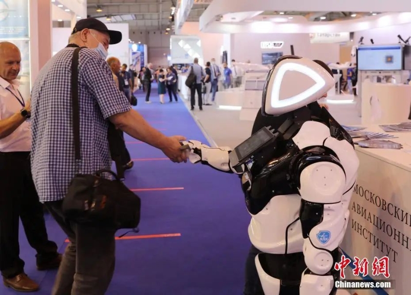 当地时间2021年7月20日，第15届莫斯科国际航空航天展览会在莫斯科州茹科夫斯基市开幕。一位参观者与展厅内机器人握手。<a target='_blank' href='/'>中新社</a>记者 王修君 摄