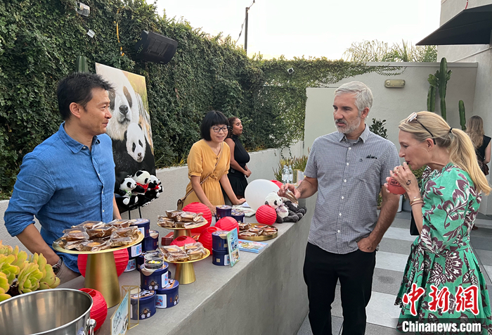 图为中国驻洛杉矶旅游办事处主任吴大伟（左一）向美国来宾介绍传统的中秋佳节，邀请他们品尝月饼。 <a target='_blank' href='/'>中新社</a>记者 张朔 摄