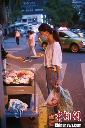手提两袋蔬菜的成都市民在选购鲜花。　受访者供图
