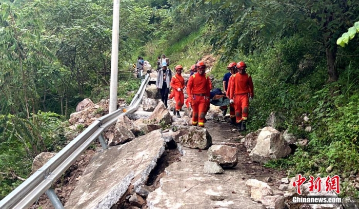 森林消防员抬着伤者通过地震中受损路段转移。 谭昊 摄