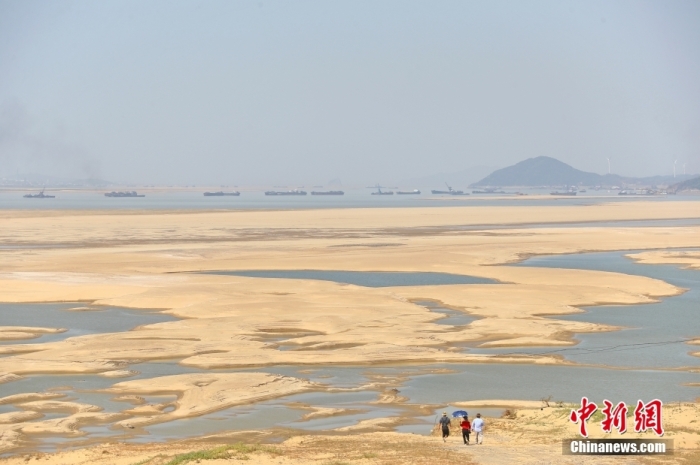 资料图：在江西省九江市都昌县鄱阳湖水域，湖床大面积裸露，几名游客走向干涸的鄱阳湖湖床。 <a target='_blank' href='/'>中新社</a>记者 刘占昆 摄