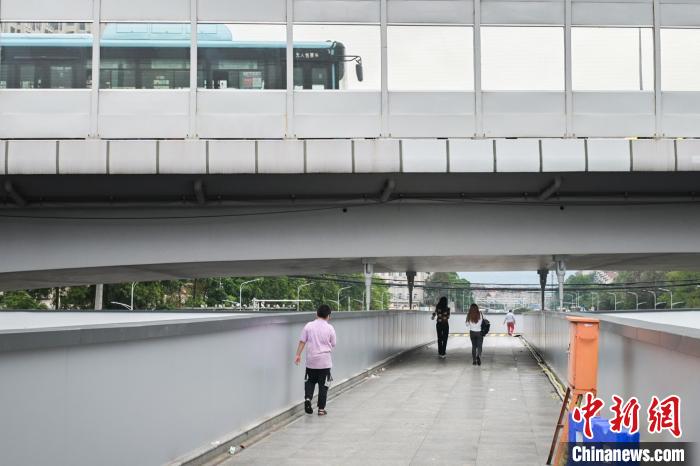 图为市民走在天桥上，公交车从头顶道路驶过。　彭心怡 摄