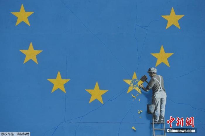 资料图：街头涂鸦大师班克西创作的画作，一名工人拿着锤子敲掉欧盟旗帜上的一颗星，寓意着英国脱欧。