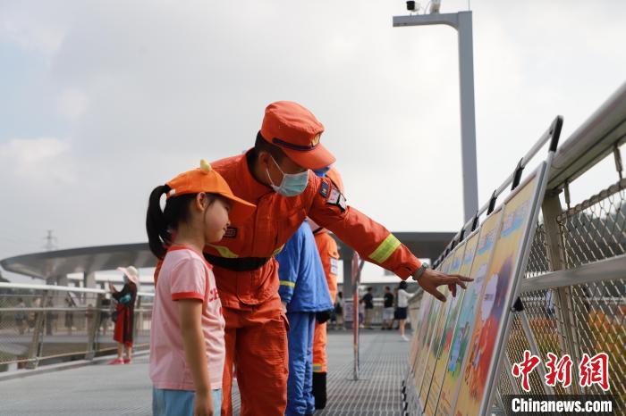 资料图：森林消防员正在防火宣传展板前与小朋友进行科普讲解。　黄山鸿 摄