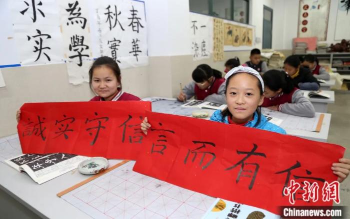 安徽省合肥市，两名学生展示“言而有信”、“诚实守信”书法作品。安君 摄