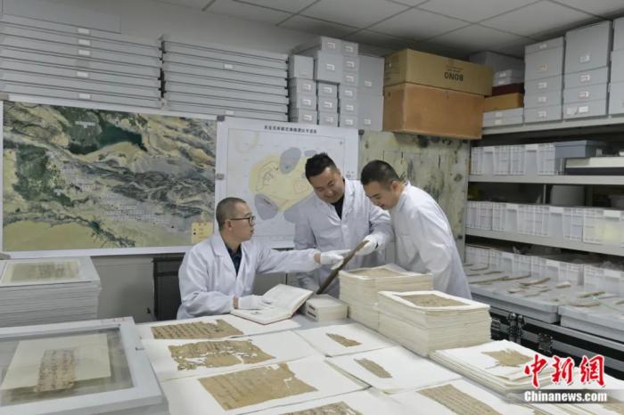 胡兴军(左一)与同事在室内整理出土文书。受访者供图

