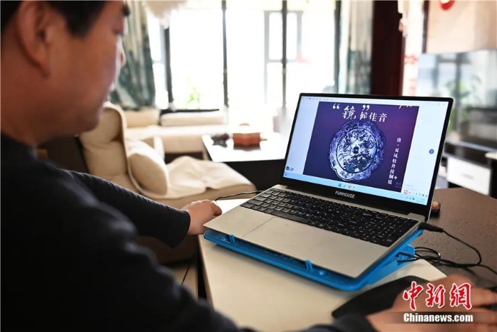 甘肃省兰州市一居民在家中使用电脑参观临洮博物馆线上展出的“唐•双凤牡丹纹铜镜”。李亚龙 摄
