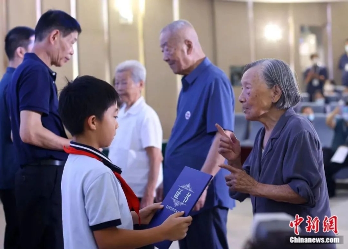 图片南京大屠杀幸存者夏淑琴(右一)、葛道荣(右二)、艾义英(右三)向南京大屠杀幸存者后代代表颁发“南京大屠杀历史记忆传承人”证书。泱波 摄