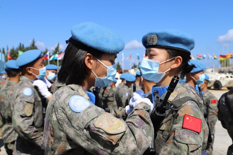 图为2021年6月16日，在黎巴嫩南部辛尼亚村中国维和营举行的授勋仪式上，接受检阅的维和女兵进场前互相整理着装。（新华社发）