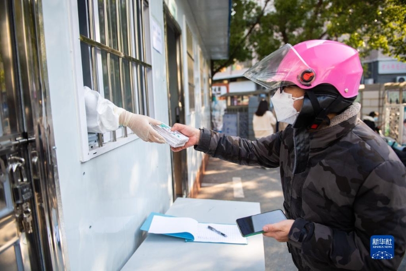 12月23日，在长沙市湘江新区望岳街道社区卫生服务中心，市民在领取防疫健康包。（图源：新华社）