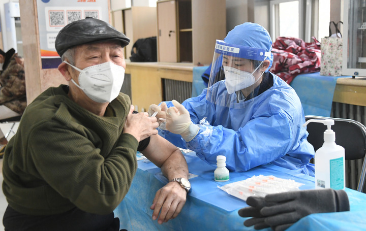 2022年12月15日，在北京市海淀区中关村街道新冠疫苗接种点，医护人员为老年人接种新冠疫苗。（图源：新华社）