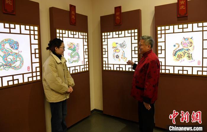 马习钦(右)游客介绍卡通造型的年画生肖兔。　苏小立 摄