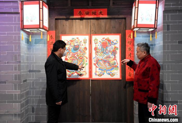 马习钦(右)向游客介绍武强木版年画《大戳锤门神》。　苏小立 摄