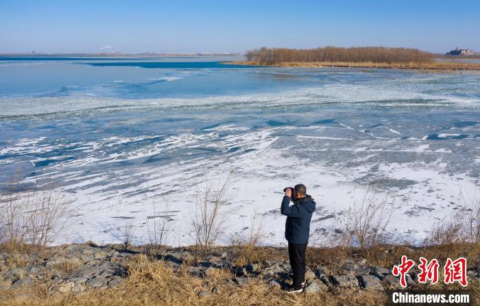春节期间，李国忠在湖心路上观察湖面结冰情况。　陈康 摄