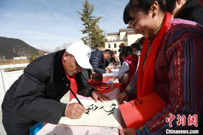 图为林芝市文联书法家协会会员向民众赠送藏文书法作品。　张力 摄
