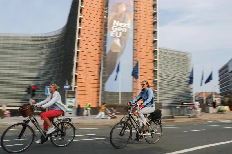 2021年9月19日，在比利时布鲁塞尔，东说念主们骑车经由欧盟委员会总部大厦。（图源：新华社）