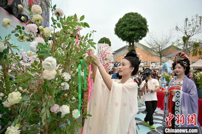 图为汉服爱好者将彩带挂在花枝上，蕴意美好。　俞靖 摄