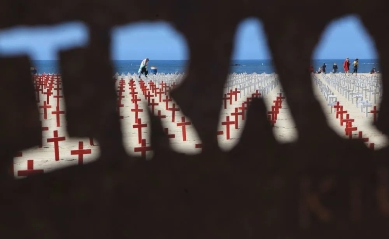 　2012年4月16日透过“伊拉克”字样的反战标牌拍摄的美国“西阿灵顿公墓”。（图源：新华社）