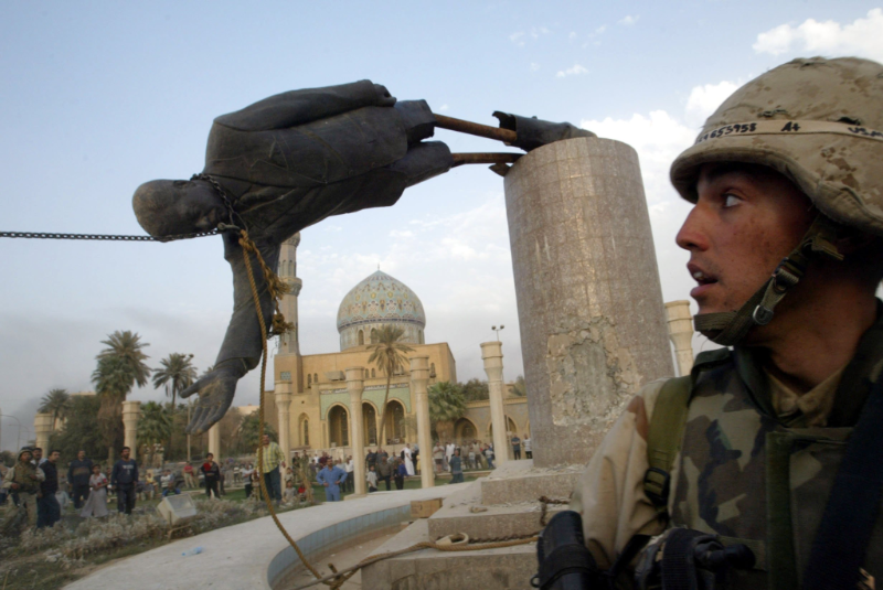 2003年4月9日，在巴格达市中心，一名美军士兵站在被拉倒的萨达姆塑像前。（图源：新华社）