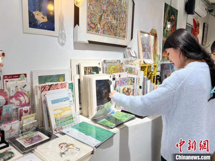 图为艺术品商店内，顾客挑选插画作品。　钟旖 摄